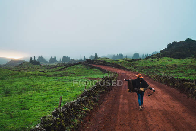Задний вид женщины, идущей по сельской дороге — стоковое фото