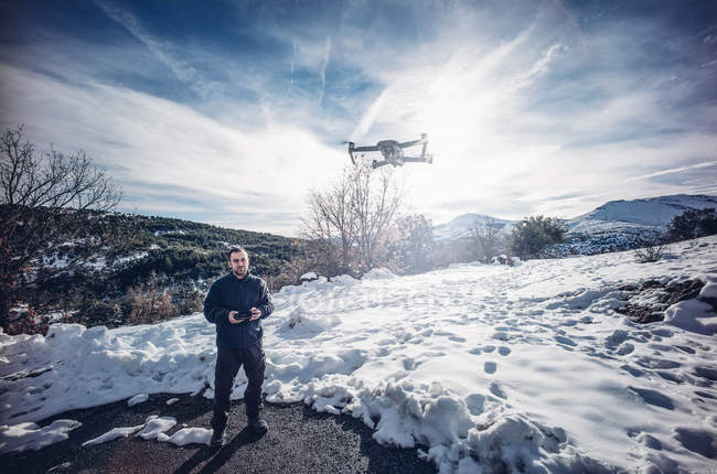 Hombre volando drone en paisaje nevado . - foto de stock