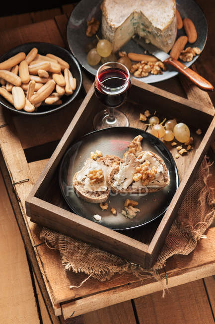 Натюрморт из подноса с различными закусками и бокалом вина — стоковое фото