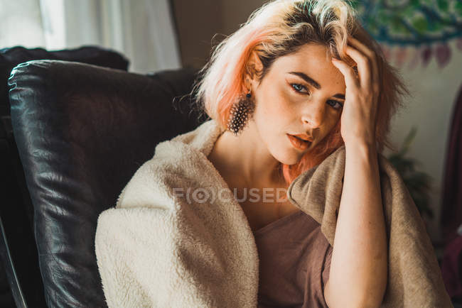 Young woman sitting in chair and looking at camera. — Stock Photo