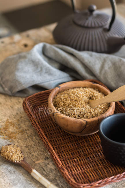Bowl with brown sugar on wicker tray and tea cup and towel — Stock Photo
