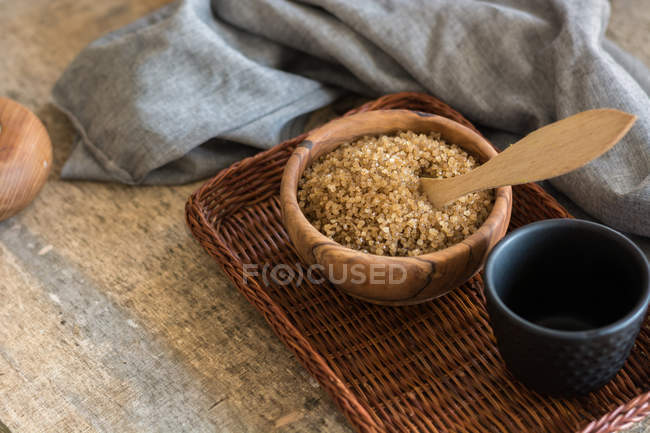 Bol avec sucre brun sur plateau en osier et tasse de thé — Photo de stock