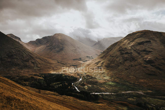 Tal mit kleinem Fluss zwischen Bergen bei bewölktem Tag. — Stockfoto