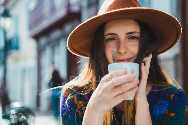 Усміхнена жінка з чашкою на терасі кафе — стокове фото