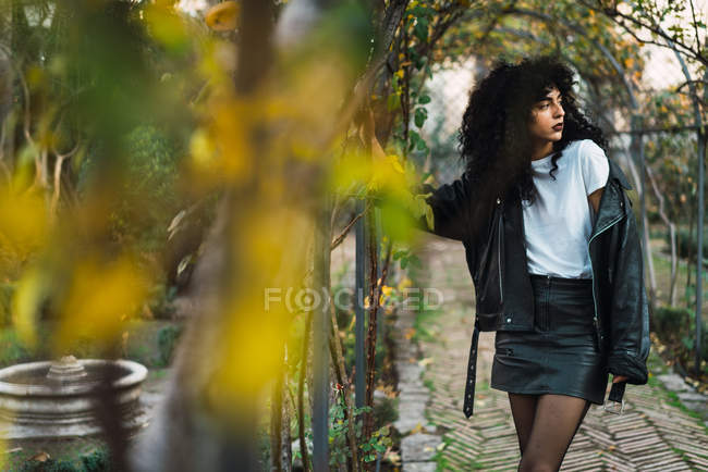 Young curly woman posing at ivy archway in park — Stock Photo