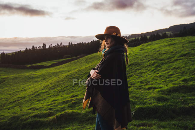 Side view of woman in hat posing over misty countryside fireld — Stock Photo