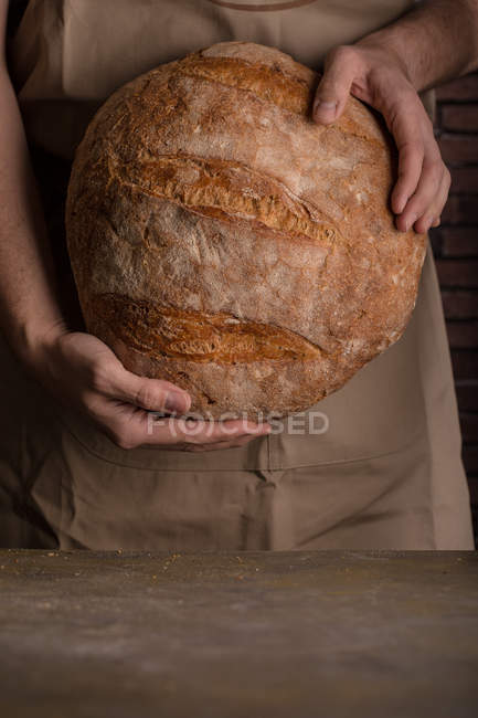 Midsection of male holding freshly baked loaf of bread — Stock Photo