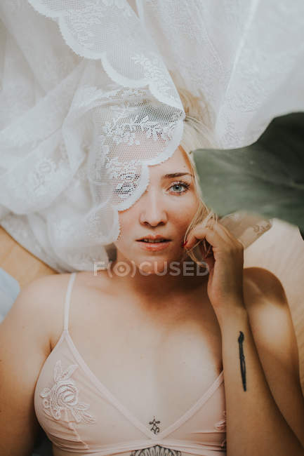 Blonde woman in lingerie posing with curtain. — Stock Photo