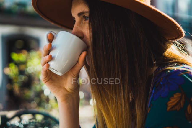 Portrait of woman drinking coffee at cafe terrace — Stock Photo