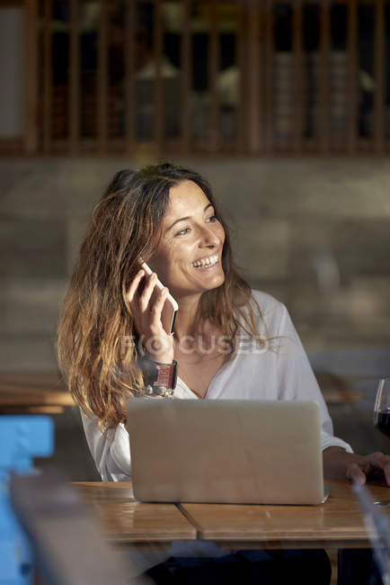 Женщина разговаривает по телефону, сидя в кафе — стоковое фото