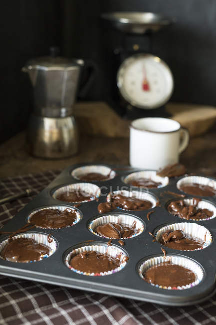 Nature morte des muffins au chocolat cru dans une plaque de cuisson préparée pour la cuisson — Photo de stock