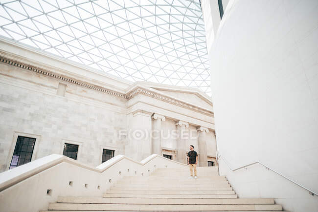 Человек, стоящий на белой лестнице в удивительном музее с красивой классической архитектурой в белом цвете. — стоковое фото