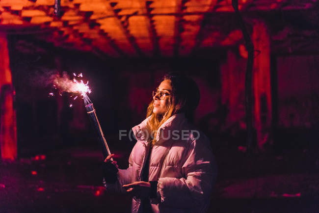 Femme posant avec une torche violette fumant dans un bâtiment abandonné — Photo de stock