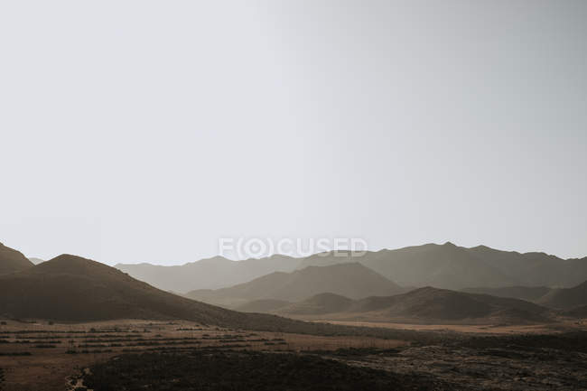 Picturesque view to small hills and gray cloudless sky. — Stock Photo