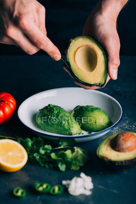 Cultivez les mains en préparant des ingrédients de guacamole dans un bol en céramique — Photo de stock