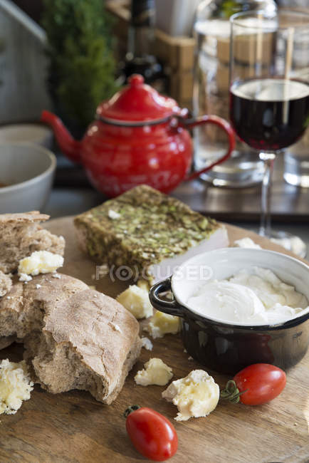Leckeres frisches Brot serviert mit Tomaten und saurer Sahne mit Speck auf Holzbrett. — Stockfoto