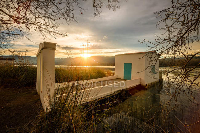 Piccolo edificio sulla riva del lago alla luce del tramonto — Foto stock