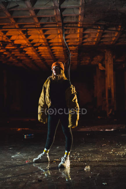 Attractive woman in stylish jacket in abandoned building at night — Stock Photo