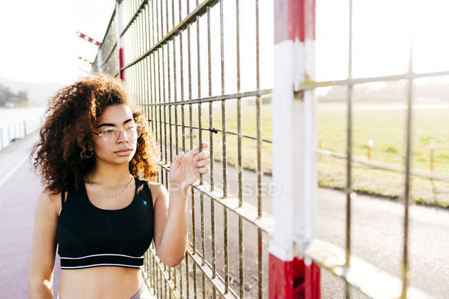 Young woman posing at grid and looking aside — Stock Photo
