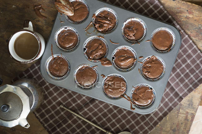 From above view of raw chocolate muffins in baking tray prepared for baking on table. — Stock Photo
