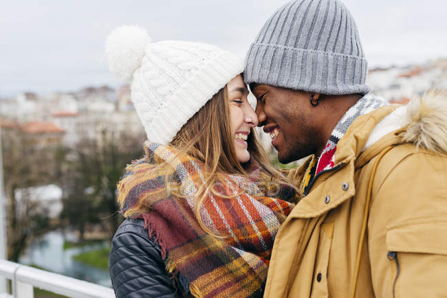 Cheerful couple embracing face to face against cityscape — Stock Photo