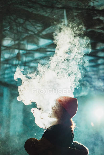 Side view of woman vaping huge cloud in abandoned building — Stock Photo