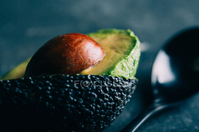 Halved avocado with seed on dark background — Stock Photo