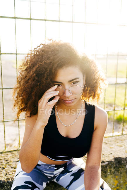 Junge Frau posiert mit Brille am Gitter — Stockfoto