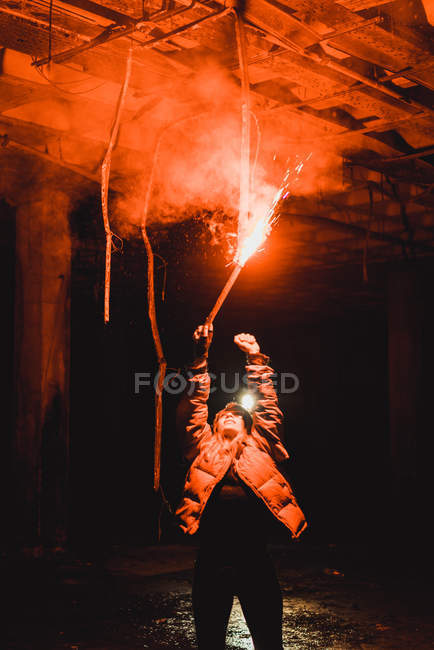 Young woman standing with red colored lighting torch in abandoned building. — Stock Photo