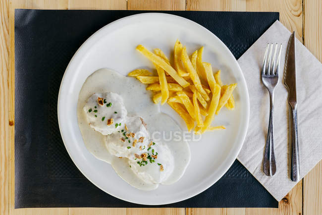 Nasello impanato con salsa e patatine fritte sul piatto — Foto stock