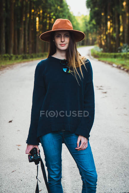Фотограф в шляпе позирует на солнечной лесной аллее — стоковое фото