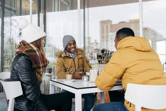 Amigos alegres sentados en la cafetería al aire libre - foto de stock