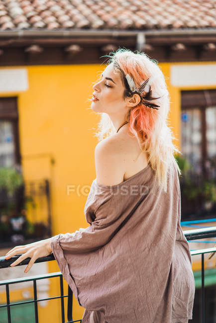 Vue latérale de la femme aux cheveux roses posant au balcon — Photo de stock