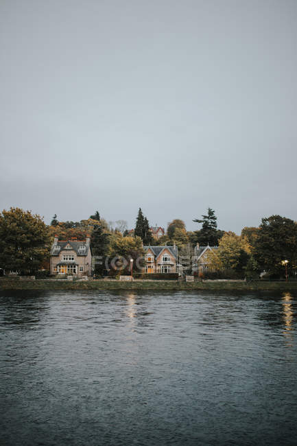 Distant view to cottage houses built at lake in cloudy day. — Stock Photo