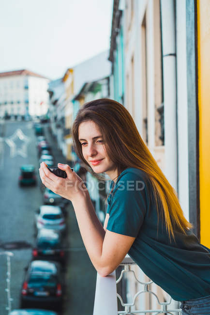 Morena encantadora posando na varanda com copo nas mãos — Fotografia de Stock