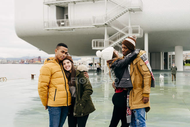 Happy couples embracing in harbor and posing to camera — Stock Photo