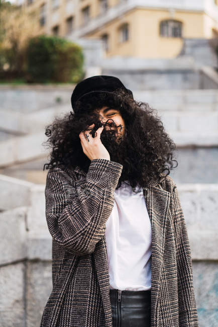 Сміється жінка ховає обличчя в кучеряве волосся в парку — стокове фото