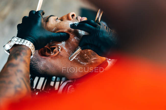 Парикмахерская бреющая борода клиента — стоковое фото