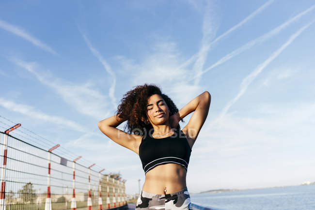 Pretty woman stretching on embankment over blue sky — Stock Photo