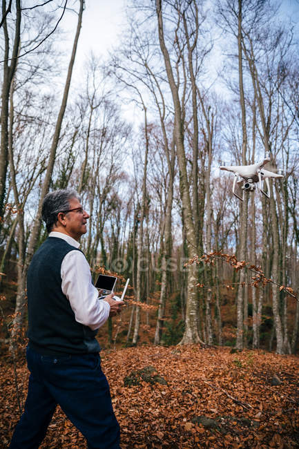 Uomo che vola drone con telecomando nella foresta — Foto stock