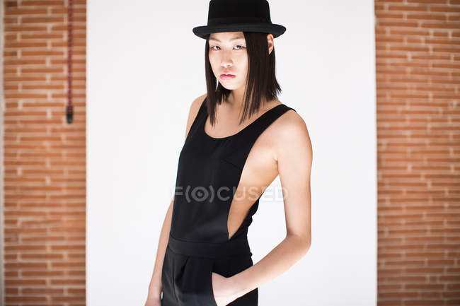 Stylische Frau mit schwarzem Hut und stylischem Overall auf weißem Hintergrund — Stockfoto