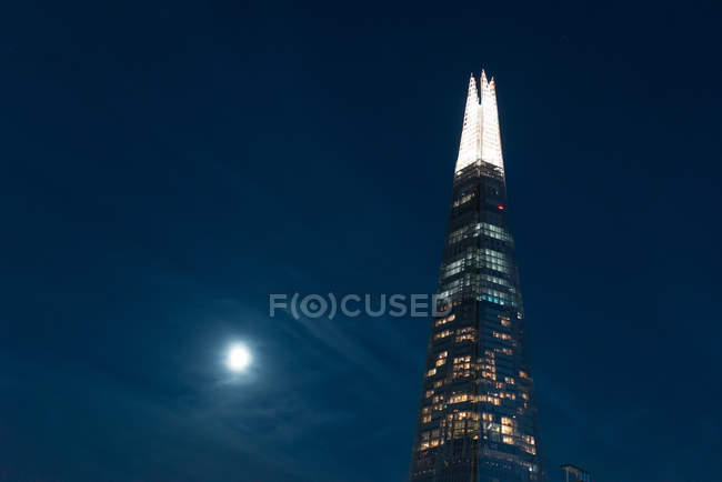 Low angle view of illuminated modern skyscraper facade over night sky — Stock Photo