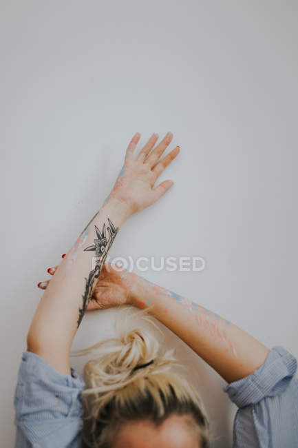 Обрізати жінку з розфарбованими татуйованими руками над білою стіною — стокове фото