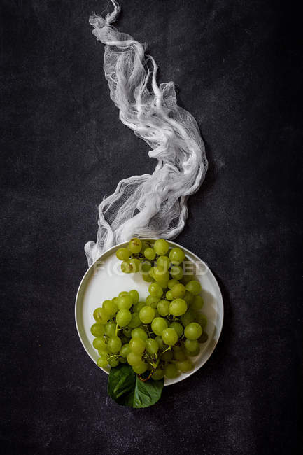 Still life of fresh grapes on plate at dark table. — Stock Photo