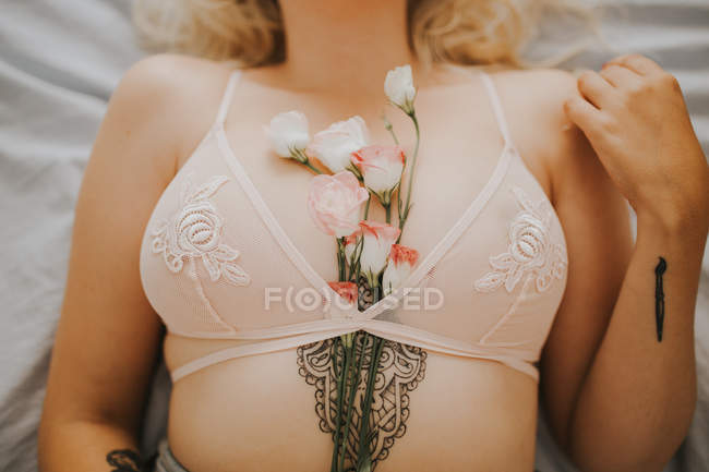 Sección media de la mujer con rosas en el sujetador - foto de stock