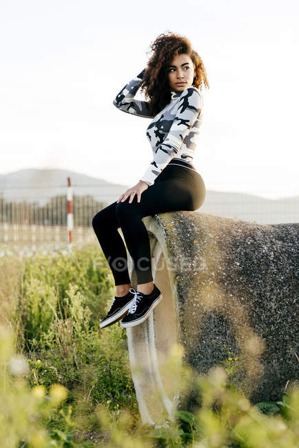 Bella donna seduta su tubo di cemento in campo — Foto stock