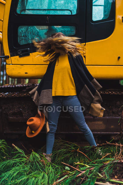 Woman shaking hair against tractor in woods — Stock Photo