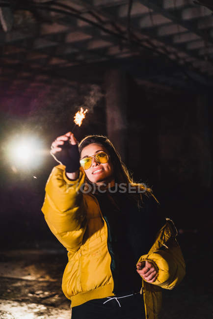 Cheerful woman with lighting sparkler — Stock Photo