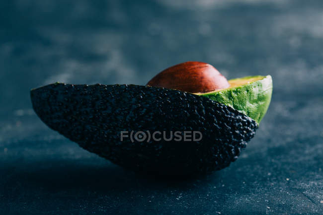 Abacate cortado pela metade no fundo escuro — Fotografia de Stock