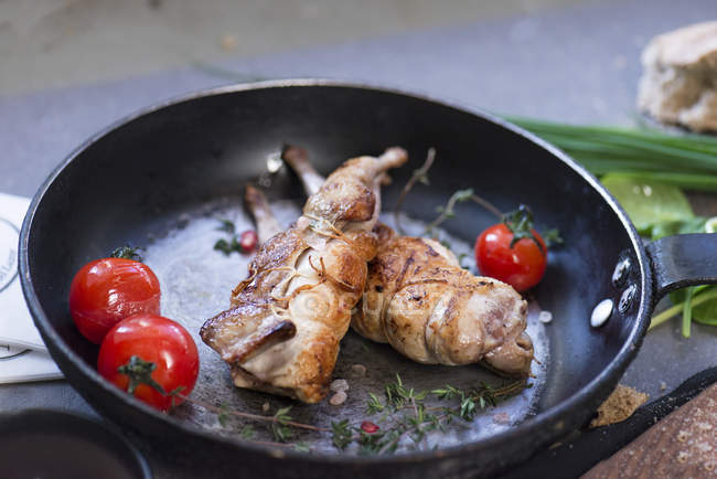 Sabroso y apetitoso pollo servido en sartén con tomates rojos frescos. - foto de stock